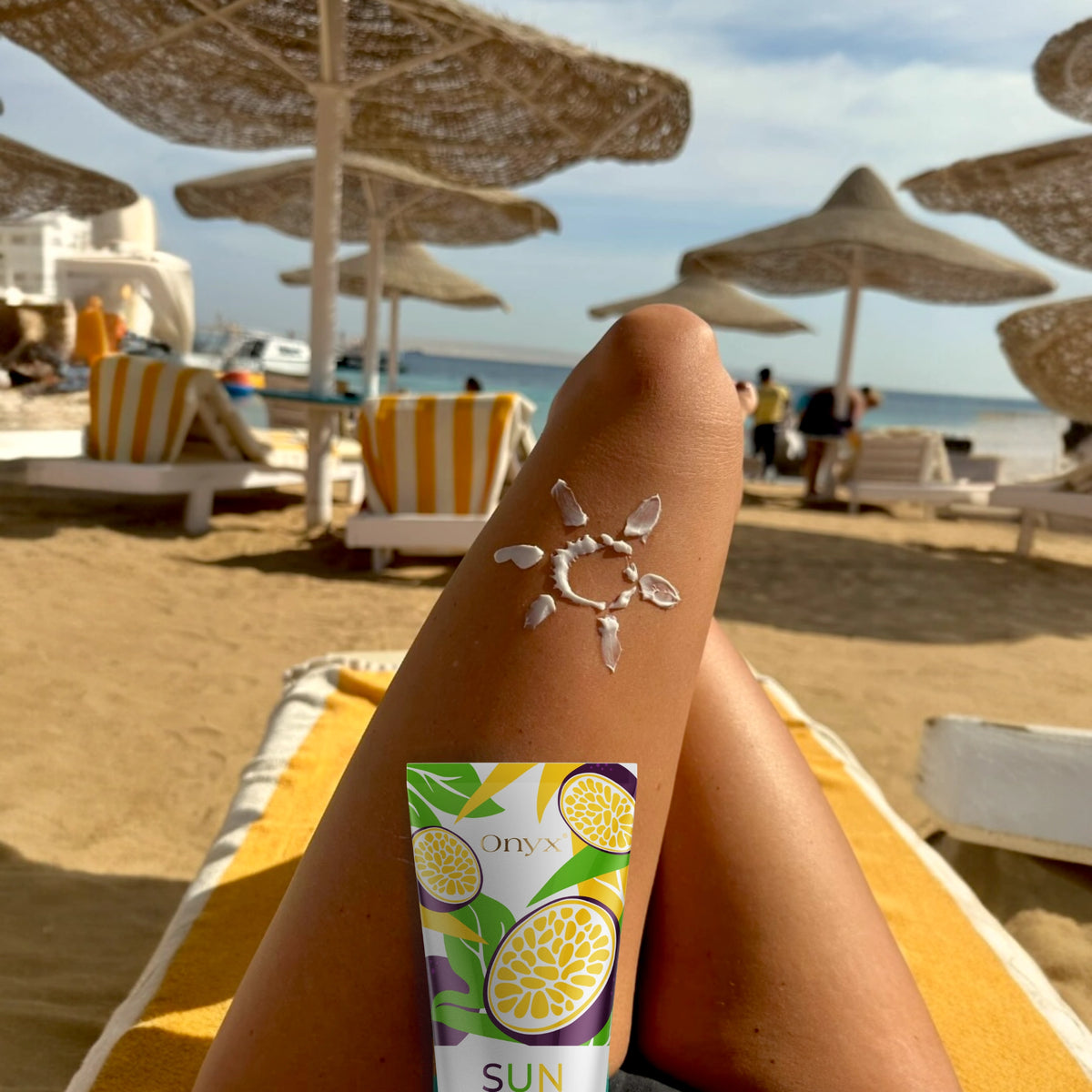 Onyx Suncolada Bräunungsbeschleuniger auf sonnengeküsstem Bein mit Sonnenmotiv aus Creme, entwickelt für das Bräunen im Freien mit natürlichen Ölen und schnell einziehender veganer Formel