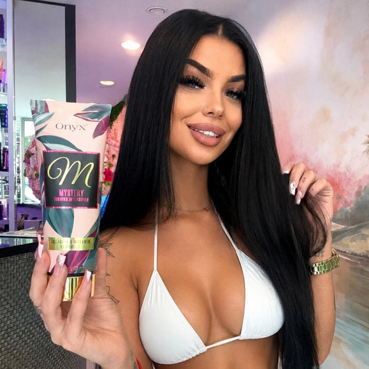 Frau im weißen Bikini präsentiert den Onyx Mystery Bräunungsintensivierer in einem Kosmetikstudio.