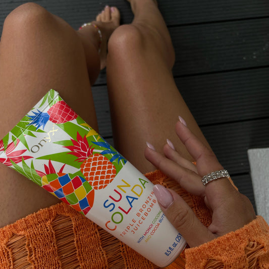 Frau mit Suncolada Bräunungslotion auf den Beinen, orangefarbener Pullover sichtbar