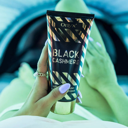 Onyx Black Cashmere Bräunungscreme liegt auf den Beinen im Solarium, grünliches Licht sorgt für elegante Atmosphäre