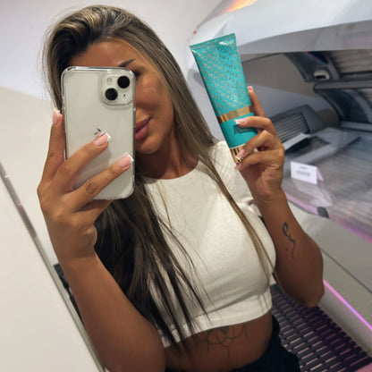 Frau macht Selfie vor Sonnenbank und hält ONYX Dark Tanning Accelerator in der Hand, ideal für gleichmäßige Bräune im Solarium