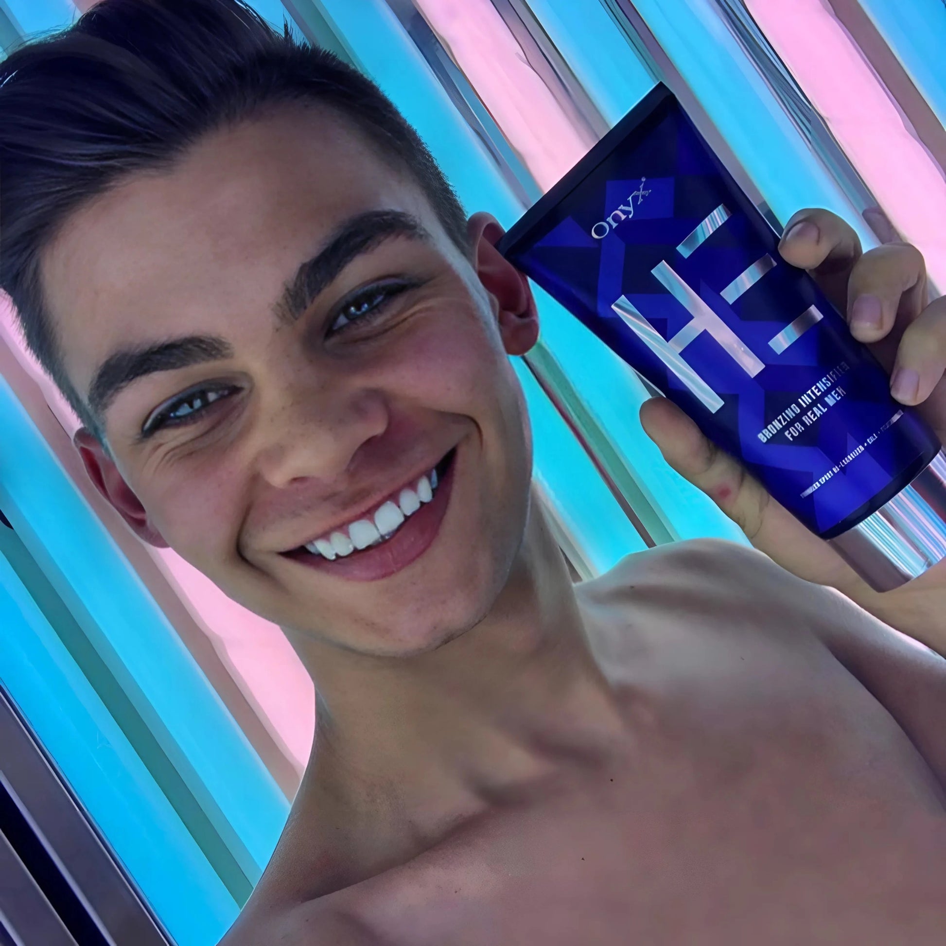 Lachender Mann in der Sonne mit definierter Bräune und Onyx HE Lotion im Vordergrund