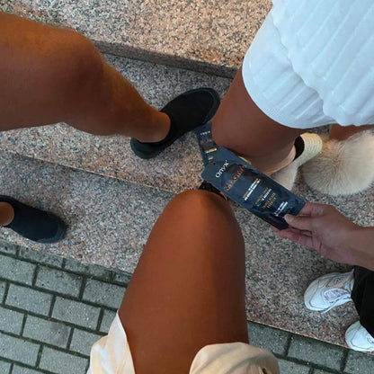 Gebräunte Beine im Sommerlook auf Treppen, Hand hält Onyx Magma Sachet