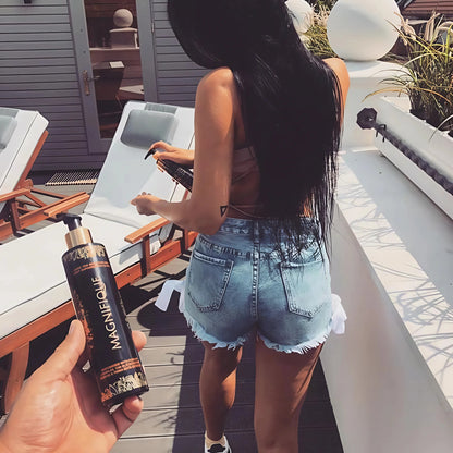 Frau im rosa Bikini präsentiert Onyx Magnifique Bräunungselixier vor Solarium – geeignet für intensive Bräune
