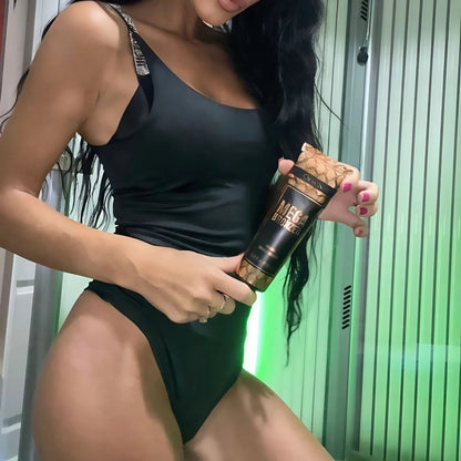 Frau vor vertikaler Sonnenbank hält Mega Bronzer Lotion, geeignet zur Vorbereitung für tiefe, streifenfreie Bräune