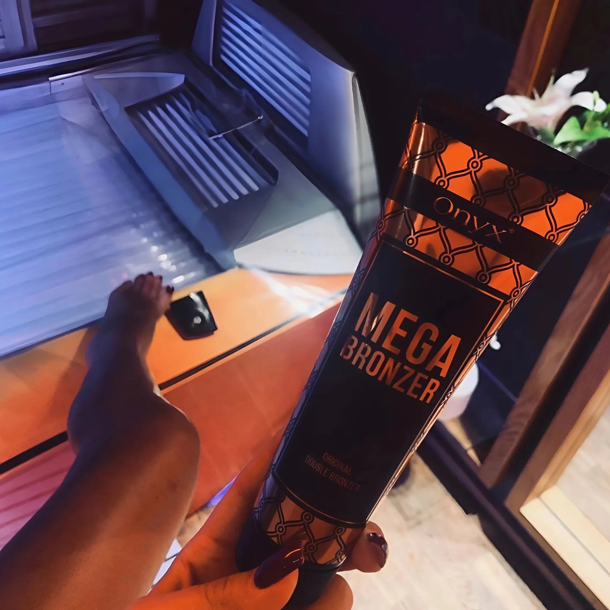 Nahaufnahme einer Hand mit Onyx Mega Bronzer in rot beleuchtetem Solarium, perfekte Vorbereitung für dunkle Bräune