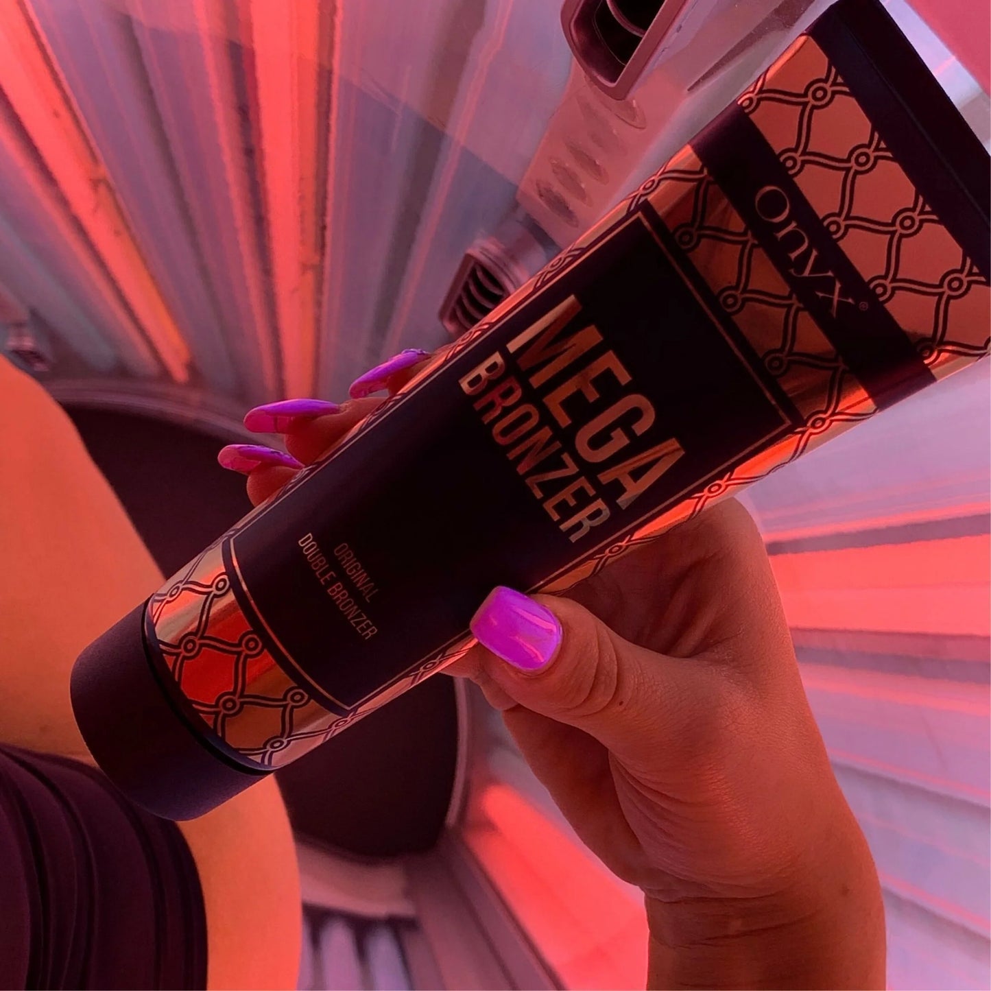 Hand mit pink lackierten Nägeln hält Mega Bronzer Lotion im rot beleuchteten Solarium, zeigt Anwendung in Echtzeit