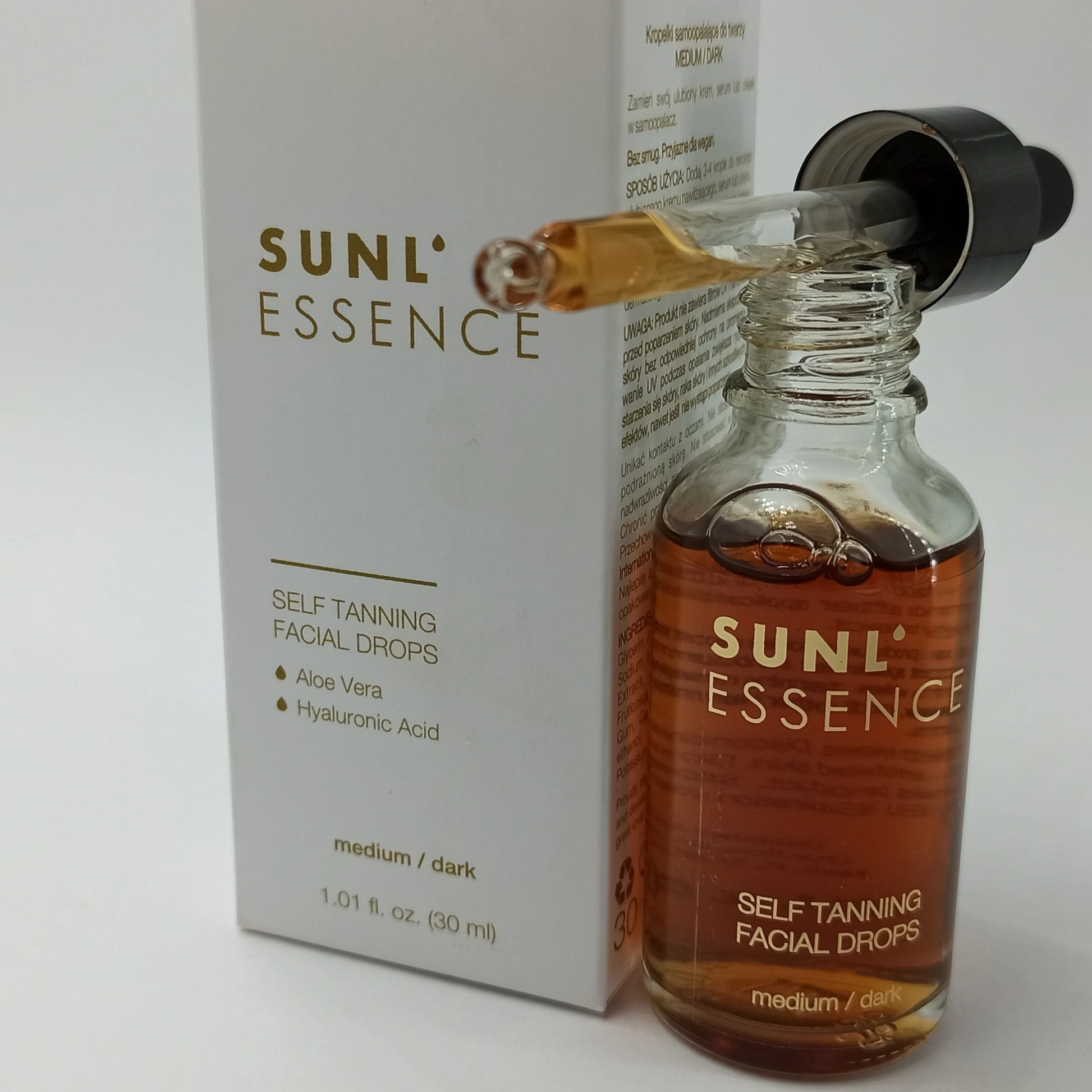 Geöffnete Flasche SUNL ESSENCE Selbstbräunungsdrops mit Pipette und weißer Verpackung im Hintergrund