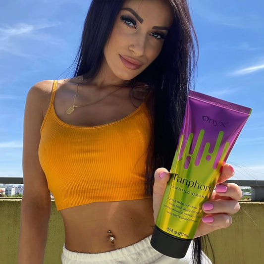 Frau im orangen Top im Freien mit Onyx Tanphoria Bräunungscreme in der Hand