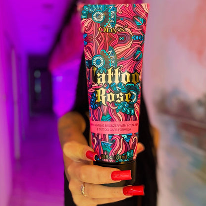 Hand mit langen roten Nägeln hält Onyx Tattoo Rose Bräunungscreme im pink beleuchteten Flur